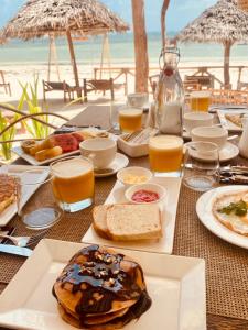 布韦朱Helwas Zanzibar Beach Hotel的海滩上的餐桌,包括食物和饮料