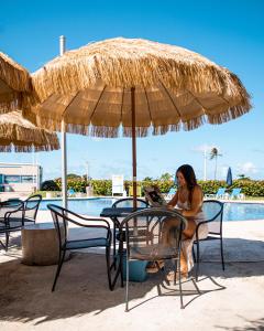 阿瓜迪亚Punta Borinquen Resort的坐在稻草伞下桌子上的女人
