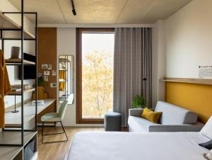 维多利亚-加斯特伊兹Kora Green City - Aparthotel Passivhaus的一间卧室配有一张床、一张沙发和一个窗口
