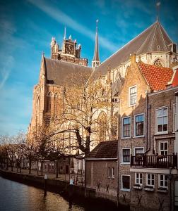 多德雷赫特Arthouse Dordrecht的一座大建筑,设有钟楼,毗邻一条河流