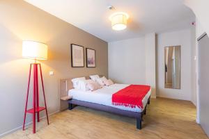 斯特拉斯堡Appart'City Confort Strasbourg Centre的一间卧室配有一张床和红色地板灯