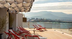 维多利亚-加斯特伊兹Kora Green City - Aparthotel Passivhaus的阳台的甲板上配有红色椅子和桌子