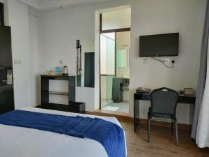 MeruTHE HOTEL EZRI的一间卧室配有一张床、一张书桌和一台电视