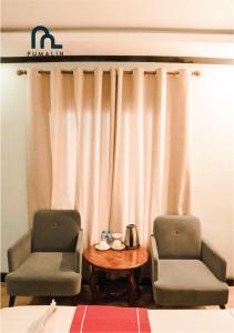 琅勃拉邦普马林别墅的窗帘前的两把椅子和一张桌子
