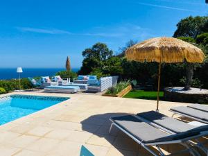 滨海卡瓦莱尔VILLA JUCANOS - Vue mer panoramique Golfe de St-Tropez的一个带椅子和遮阳伞的庭院和一个游泳池