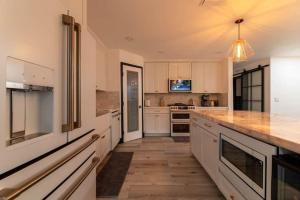 圣佩德罗Modern San Pedro Home Sleeps 12的厨房铺有木地板,配有白色橱柜。