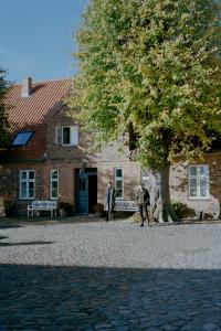 Strukkamp auf FehmarnHistorisches Bauernhaus Fehmarn的两个人站在一棵树的建筑前