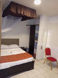 基苏木Beach View Hotel - Kisumu的一间卧室配有一张床和一张红色椅子