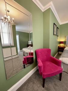 布莱顿霍夫Regency Apartment - Marine Square By Crown Gardens Holiday Homes的卧室配有粉红色的椅子和镜子