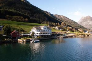 菲耶兰Fjærland Fjordstove Hotell - Huseby Hotelldrift AS的水体岸边的白色大房子