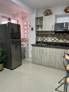 伊塔圭Lindo Apartaestudio cerca al centro的厨房配有黑色冰箱和水槽