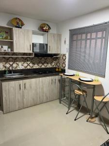 伊塔圭Lindo Apartaestudio cerca al centro的厨房配有木制橱柜、2张桌子和1扇窗户。