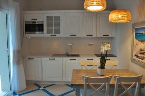 皮诺港Villa Aquamarina Pintadera Blu的厨房配有白色橱柜和花瓶桌子