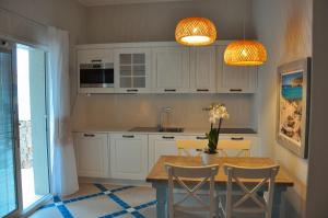 皮诺港Villa Aquamarina Pintadera Blu的厨房配有白色橱柜和一张带椅子的木桌