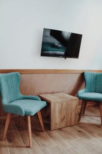 亚霍里纳Vila Jelena的两把椅子和一张桌子,墙上配有电视