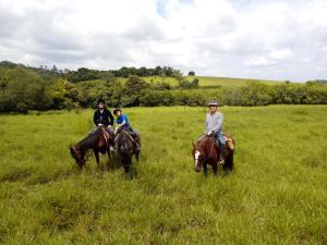 巴埃彭迪Pouso do Tropeiro - Cavalgadas Roseta的三人在草地上骑马