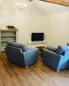 PattishallTilly’s stable的客厅配有2把蓝色椅子和电视