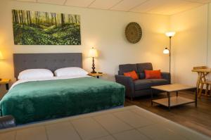 ManitowaningWayside Motel Manitoulin的一间卧室配有一张绿色大床和一张沙发