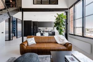 墨尔本New York Converted Warehouse Apartment in Richmond的一间带棕色沙发的客厅和一间厨房