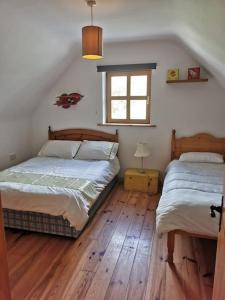 莱特肯尼Comfortably Crolly Holiday Home的卧室设有两张床,铺有木地板,设有窗户。