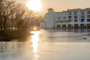 济州市Ecoland Hotel的一条河上的建筑,太阳落在后面