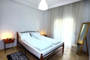 兹拉马Ourania Apartment的一间卧室配有一张带白色床单的床和一扇窗户。