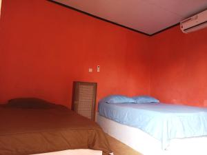 龙目岛库塔Perwita Homestay的一间卧室设有两张床和红色的墙壁