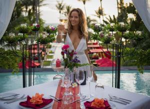 Haad PleayleamKupu Kupu Phangan Beach Villas & Spa by L'Occitane - SHA Plus的女人在桌子上拿着一杯葡萄酒