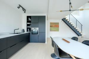 布鲁塞尔Appartement tendance 1 chambre et mezzanine proximité Châtelain, Brugmann的厨房配有黑色橱柜、桌子和楼梯