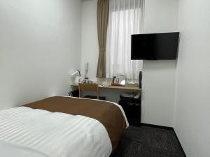 东京Ueno Urban Hotel Annex的酒店客房配有一张床、一张书桌和一台电视。