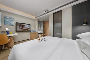 广州凤悦轻尚酒店(广州白云机场店)的卧室配有一张白色大床和一张书桌