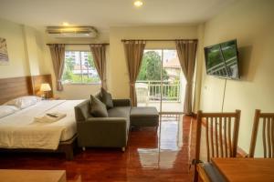 芭堤雅市中心Baan Chuan Chom Pattaya的一间卧室配有一张床、一张沙发和一把椅子