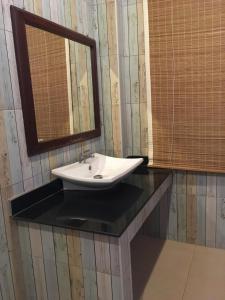 盼武里河畔度假酒店的浴室设有水槽和镜子,位于柜台上