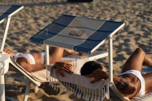 帕埃斯图姆索加利斯酒店的一群人躺在沙滩上的草坪椅上