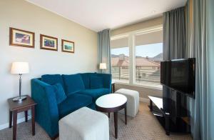 卑尔根卑尔根市斯堪迪克酒店的客厅配有蓝色的沙发和电视
