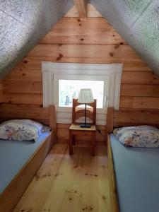 MedsėdžiųNamelis su ofuro vonia prie Plateliu ežero的小屋内带两张床和椅子的房间