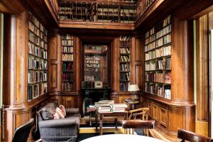 科英布拉眼泪庄园酒店 - 小型豪华酒店的书架和椅子上的人的图书馆