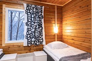 伊瓦洛Arctic River Resort的木制客房内的一间卧室,配有一张床