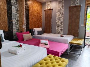 洛坤府JB Grand Resort的一间设有4张床、粉色和白色床单的客房