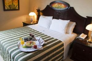 瓜达拉哈拉赌场广场酒店的一间酒店客房,配有一张床铺,上面放着一个食物托盘