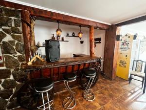 Şinca VecheBârlogul Urșilor的一间设有酒吧、凳子和电视的房间