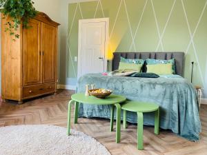 宾斯霍滕De Oude Pastorie的一间卧室配有床和两张绿桌