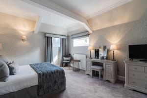 格伦罗西斯巴尔伯尼豪斯酒店的一间卧室配有一张床、一张书桌和一台电视