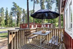 科尔莫登First Camp Kolmården-Norrköping的甲板上配有遮阳伞的野餐桌