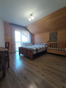 米库利钦Кам'яний двір的卧室配有一张床铺,位于带木墙的房间内