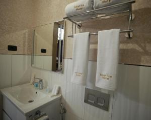 巴库West inn Hotel & Restaurant的浴室配有盥洗盆、镜子和毛巾