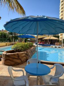 卡达斯诺瓦斯Locação Caldas Novas 1410的游泳池旁的蓝色桌椅和遮阳伞
