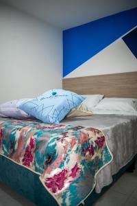 波哥大Hotel Santo Tomas Bogota的一张带色彩缤纷的被子和枕头的床