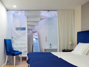 维塞乌Apartamentos Premium Familiares - Loft Guesthouse BeMyGuest Viseu的一间卧室设有一张床、一把蓝色椅子和一个螺旋楼梯