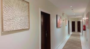 吉达Ghima Jeddah的走廊上设有白色的墙壁和墙上的绘画作品
